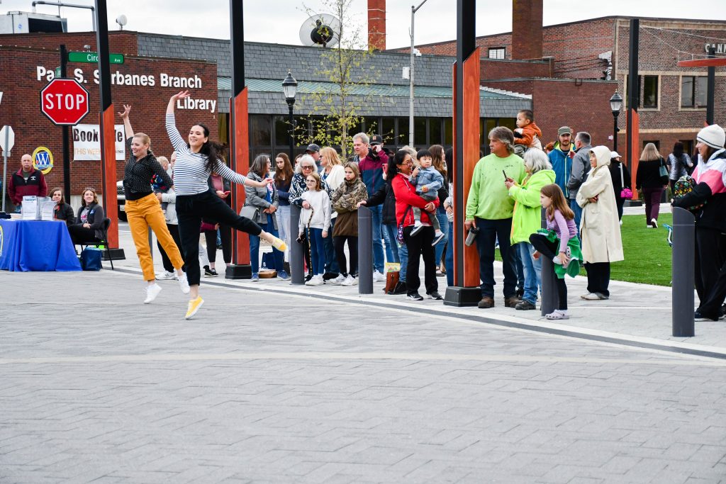 Two people dancing on the street with a crowd behind them.